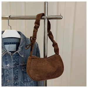 Détail du sac baguette en daim marron avec bandoulière à volants et détail de noeud