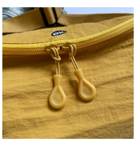 Detail of mustard yellow nylon chest bag with double zippers and black ok embroidery