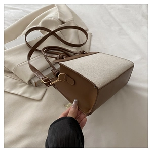 Close-up of beige canvas and brown leather crossbody bag with metal buckle detail