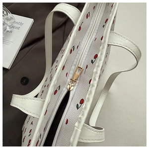 Detail of white cherry print tote bag featuring smooth PU leather and gold metal zipper