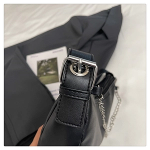 Close-up of silver metal buckle and fine stitching on black leather chain bag