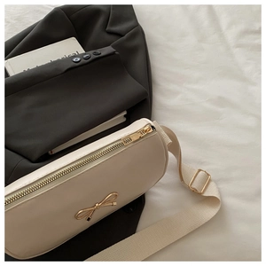 Close-up of cream square crossbody bag featuring golden bow detail and fabric strap