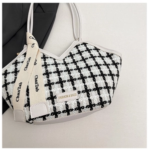 Détail de la texture en tweed noir et blanc et de la plaque métallique sur le sac fourre-tout
