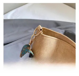 Detail of light brown canvas bag with golden metal hook and ethnic jacquard strap