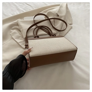 Detail of minimalist beige canvas and brown leather crossbody bag with knot handle