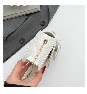 Detailansicht der weißen Mini-Tasche aus Leder mit Goldkette und Perlen-Schleife