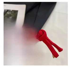 Macro detail of high-quality metal zipper and knotted red suede pull on mini square bag