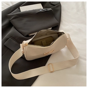 Détail du sac sous le bras crème montrant l'intérieur spacieux et le nœud métallique