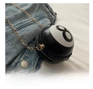 Close-up of number 8 billiard ball shaped handbag with gold chain strap on denim