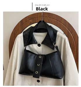Detail of minimalist black matte leather underarm bag with wide strap and gold hardware