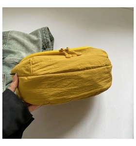Close-up of a vibrant yellow nylon crossbody bag with smooth dual zippers and puffy texture