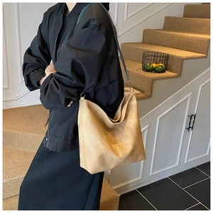 On-shoulder view of large khaki tote bag with colorful woven strap on model