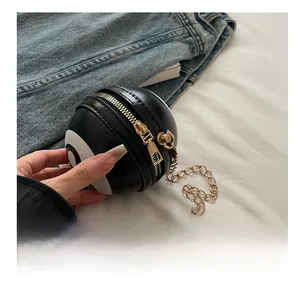 Detail of a 8-ball shaped black leather sphere bag with gold zipper on denim fabric