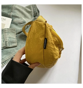 Detail of bright yellow nylon crossbody bag with Fashion tag and waterproof fabric texture
