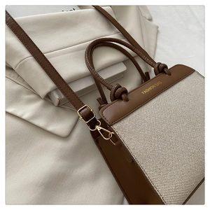 Detail of brown leather and beige tweed tote with Fashion Bag text and gold hardware