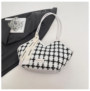 Détail du sac cabas en tweed avec motif à carreaux noir et blanc et plaque de la marque