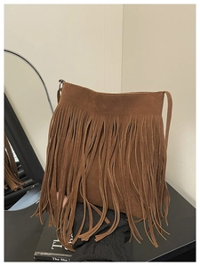 Détail du sac seau en daim marron avec de longues franges et un design rétro à pompons boho
