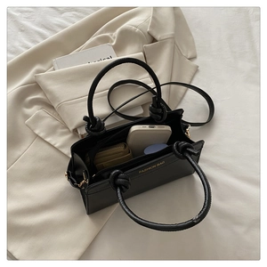 Detail of spacious interior of black PU leather tote with knot handle and gold branding