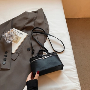 Minimalist black pebble leather handbag with silver zipper and adjustable crossbody strap