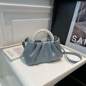 Light blue pleated cloud bag with pearl handle and shoulder strap shown from a 45-degree angle