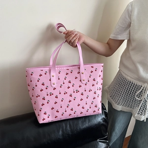 Pink tote bag with cherry print and gold rivets shown in a stylish side view profile