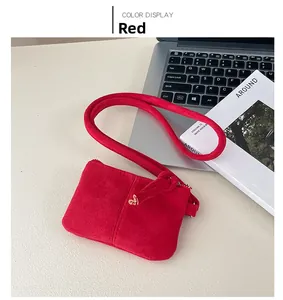 Detail of red corduroy neck pouch with gold heart zipper pull on a desk setup