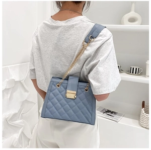 Close-up of the quilted stitching and gold metal buckle on a light blue chain shoulder bag