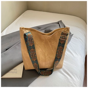 Detail of khaki suede tote bag with geometric pattern wide strap on white bedding