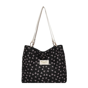 Sac cabas noir matelassé avec nœuds roses et bandoulières en cuir blanc sur fond blanc