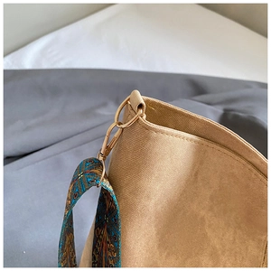 Detailed shot of khaki canvas tote with ethnic patterned wide strap and gold hardware