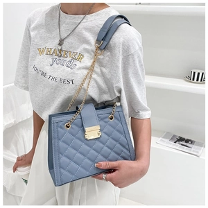 Detail shot of light blue quilted PU leather handbag with gold chain strap and metal clasp