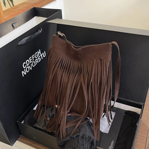 Sac seau à franges en daim marron au style bohème présenté dans un coffret cadeau noir