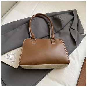 Detail of brown vintage leather tote with white stitching on gray blazer background