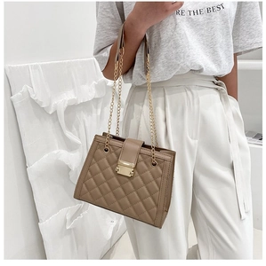 Detailed view of beige quilted leather shoulder bag with golden chain and square lock