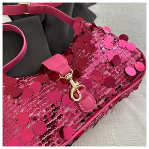 Detailed shot of pink sequin shoulder bag with leather strap and golden metal buckle
