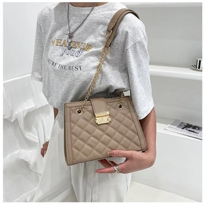 Detail of quilted beige shoulder bag with gold metal lock and elegant chain strap