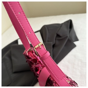 Detail of pink sequin handbag showing leather strap and gold metal buckle