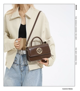 Sac à main en cuir verni marron foncé avec logo M doré porté en sac bandoulière chic