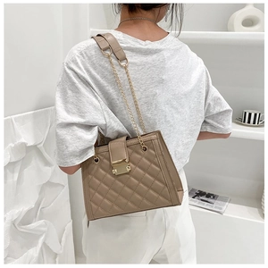 Rear view of model wearing khaki quilted crossbody bag with golden chain and clasp