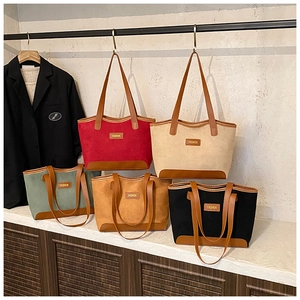 Close-up of suede tote bags in various colors with contrasting leather trim and logo