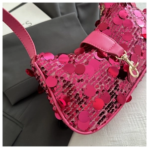 Detailed close-up of dark pink sequined baguette bag featuring a gold metal buckle