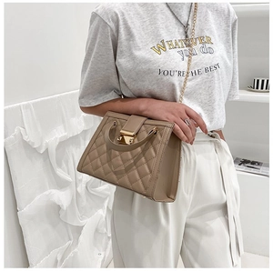 Detail of beige quilted chain handbag featuring a golden swivel lock and leather strap