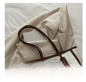Dettaglio della borsa tote in tessuto bianco con manici in pelle marrone su sfondo neutro