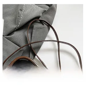 Détail d'un sac à bandoulière en cuir brillant marron foncé avec fines anses rondes