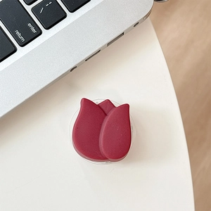 Gros plan d'un support de téléphone en forme de tulipe rouge sur un bureau blanc épuré