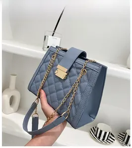 Detail of greyish-blue quilted handbag featuring golden metal buckle and chain strap