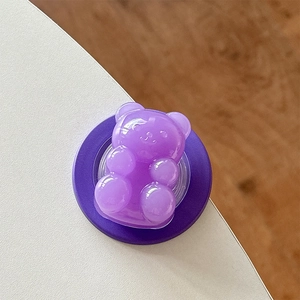 Macro view of purple gummy bear magnetic phone grip on a minimalist desk surface