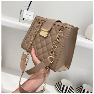 Detail view of khaki quilted crossbody bag with gold square lock and chain strap