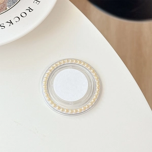 Detail view of a round Griptok phone holder with white pearls and gold accents