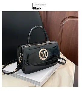Détail d'un sac en cuir verni noir brillant avec boucle métallique dorée logo M